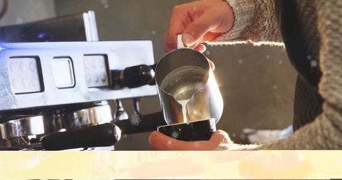 Barista steaming milk for latte art in cozy cafe