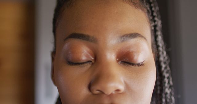 Close-up of African woman with eyes closed, conveying sense of peace and relaxation. Ideal for wellness campaigns, mindfulness blogs, relaxation tips, meditation apps, and promoting self-care.