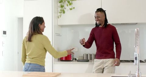 Smiling african american man and indian woman interacting in bright modern kitchen