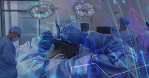 Surgeon securing mask and gown as sterile surgical team prepares for high-tech operation