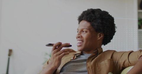 Man speaking into smartphone while relaxing on living room sofa casual home communication