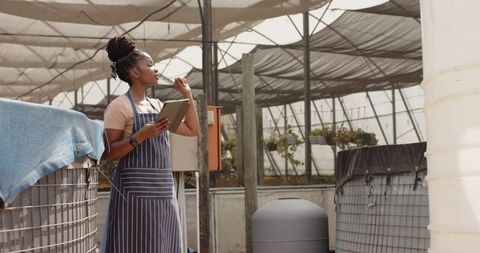 Female horticulturist using tablet for greenhouse inspection