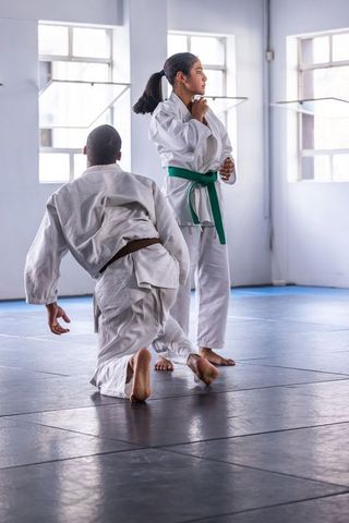 Martial arts partners in white gis sparring in bright dojo