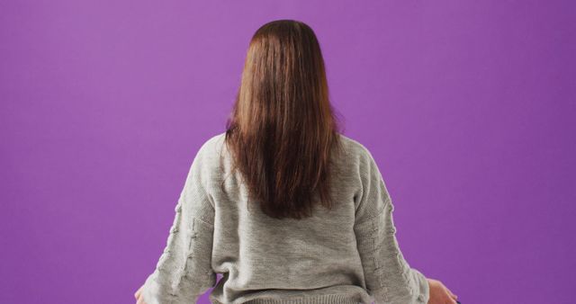 Perfect for use in wellness and self-care content, this image shows a woman practicing meditation on a purple background. Ideal for websites, blogs, and social media posts promoting mindfulness, relaxation, and mental health awareness. The image conveys a sense of tranquility and peace, making it suitable for illustrating articles on yoga, spiritual practices, and holistic health.