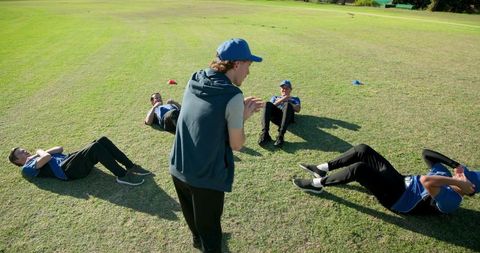 Youth sports team doing core training with coach on grass field for teamwork and fitness
