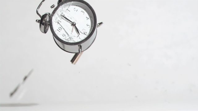 Alarm clock caught in moment of destruction as it is hammered against a white background, showcasing intricate details of collapse. Great for concepts related to time management, breaking habits, or stress. Ideal for use in marketing materials that wish to illustrate urgency, end-of-cycle, or releasing stress. Useful for blogs or campaigns focusing on productivity both aligned and at odds with better work-life balance.