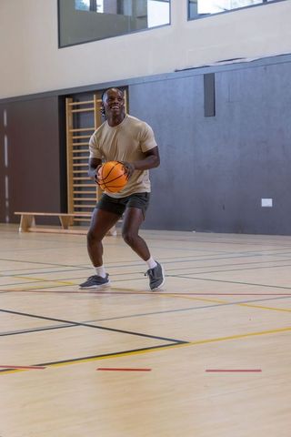 African american man preparing to pass basketball on indoor gym court during training