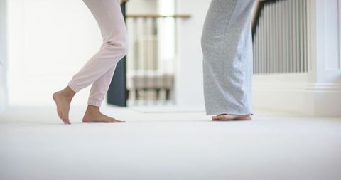 Barefoot diverse women standing on soft hallway carpet wearing casual loungewear and skirt