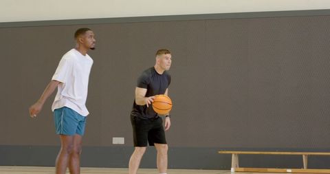 Competitive indoor basketball drill dribbling player facing defender gym training session