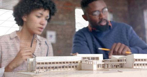 Collaborating architects examining scale model and blueprints in loft with digital overlay