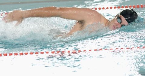 Male Athlete Swimming Freestyle Competitively in Aquatic Center