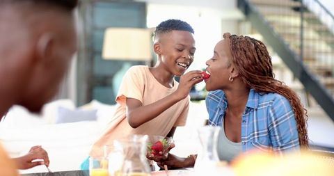 Son Feeding Happy Mother Strawberry During Family Dinner