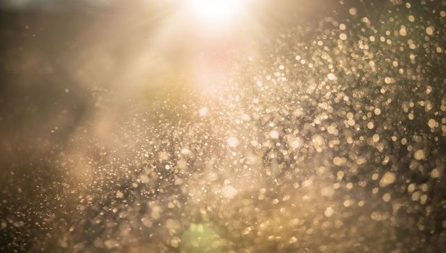Golden backlit water droplets scattering sunlight, bokeh sparkle and warm flare