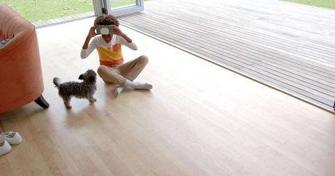 Curly-haired boy interacting with vr headset and curious dog