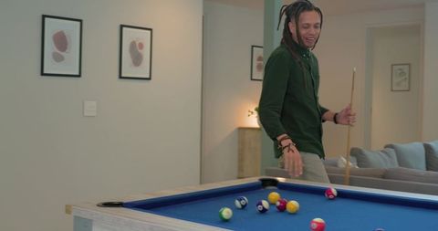 African american man playing pool at home aiming cue in contemporary lounge interior