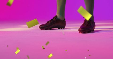 Athlete celebrates in soccer cleats and green socks with flying gold confetti