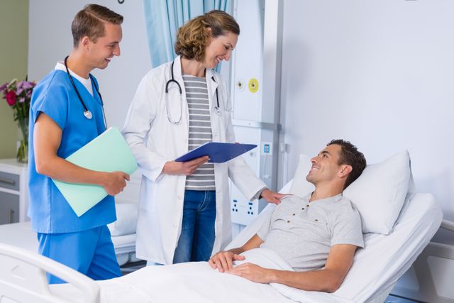 Smiling doctors talking to patient in hospital bed