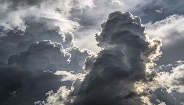 Rising cumulonimbus towers backlit by sunlight with silver linings and crepuscular rays