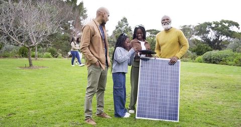 Multigenerational family exploring solar energy in park while using tablet for learning