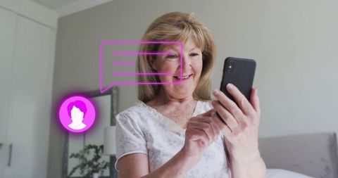 Senior Woman Smiling While Using Smartphone in Bedroom