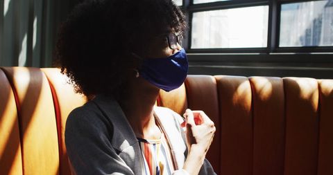 Businesswoman Wearing Face Mask Looking at Window in Café