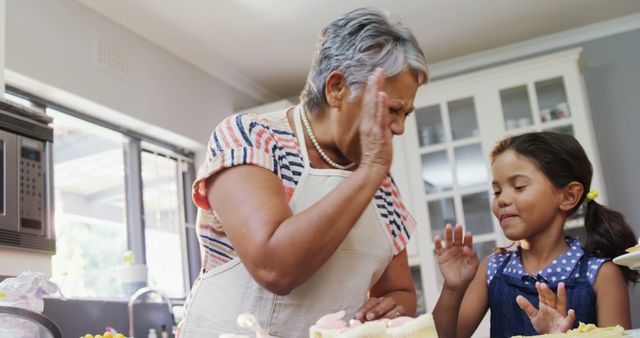 Grandmother Giving High-Five to Granddaughter in Kitchen - Download Free Stock Images Pikwizard.com