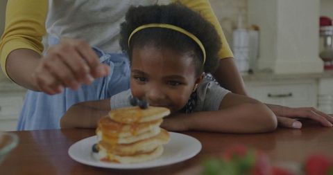 Joyful Child Anticipating Delicious Pancakes Topped with Blueberries