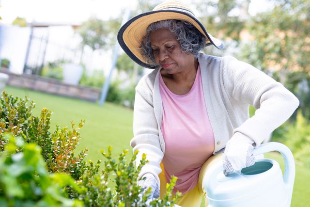 Senior african american woman watering plants in garden, copy space. Retirement, senior health, inclusivity and senior lifestyle concept.