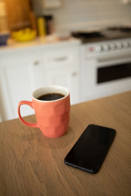 Coffe cup and smartphone on a table in the kitchen. Domestic life and spending time at home. 