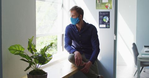 Man Contemplating While Wearing Mask in Modern Office