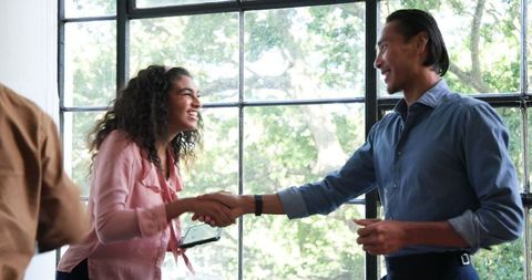 Colleagues Shaking Hands in Modern Office with Big Windows