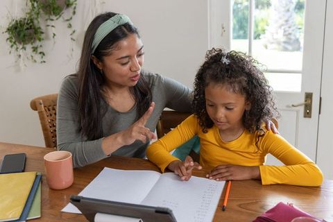 Asian woman tutoring african american girl using tablet and notebook homeschool learning