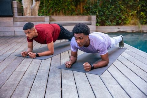Two Male Friends Exercising Planks by Backyard Pool