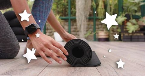 Rolling black yoga mat on outdoor deck with smartwatch and leggings