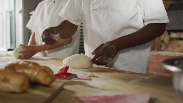 This video captures diverse bakers working together preparing sourdough in a small bakery. Ideal for use in content focusing on teamwork, culinary skills, independent businesses, artisan baking, and diversity in workplaces.