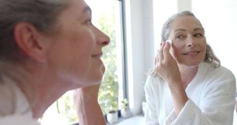 Mature Woman Enjoying Morning Skincare Routine in Bright Bathroom