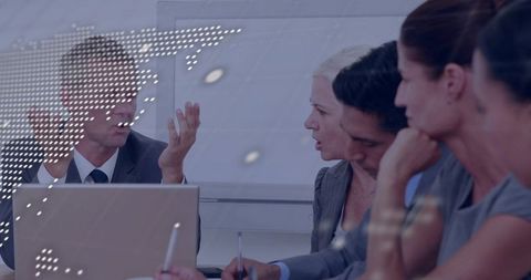 Business leader addressing team during strategic meeting with dotted world map overlay and laptop