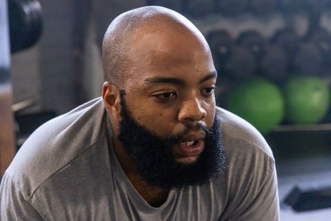 African american athlete catching breath and sweating after intense gym training session