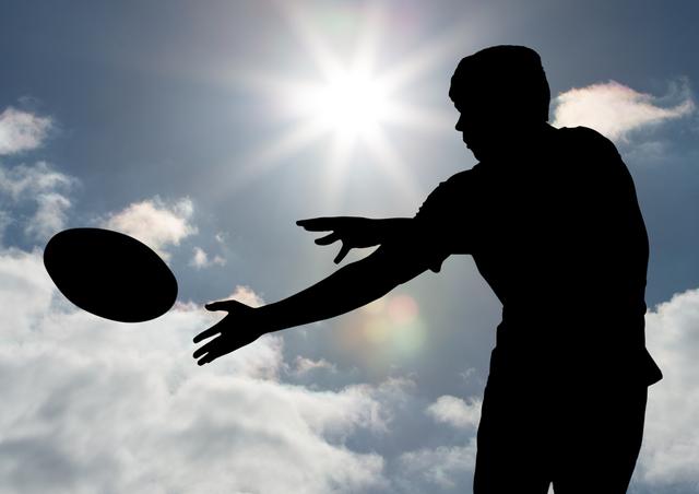 Digital composition of silhouette of player catching a rugby ball against sky in background
