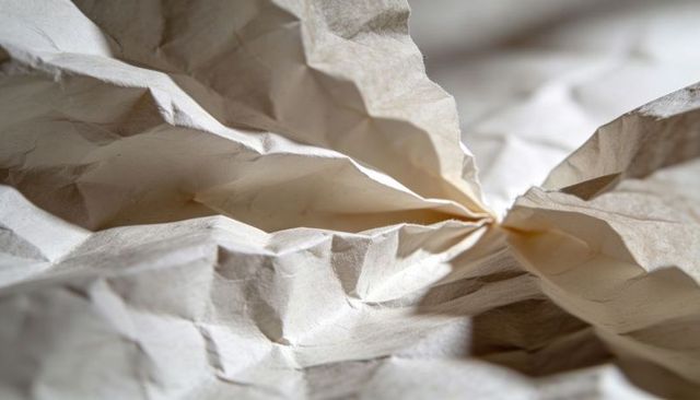 Crumpled Beige Paper Macro Texture Showing Central Pinch Crease Folds and Natural Fibers