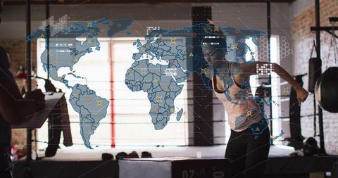 Female athlete training boxing in industrial gym with holographic world map overlay