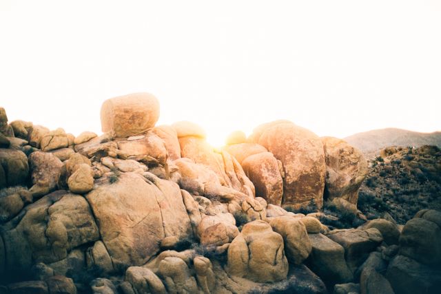 Desert landscape at sunset with sunlight illuminating boulders. Suitable for use in travel magazines, nature documentaries, or inspirational artwork emphasizing the beauty and tranquility of natural landscapes.