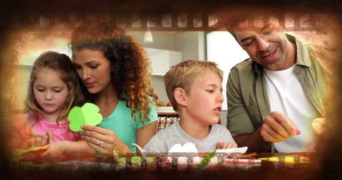 Family creating clover paper crafts at kitchen table, parents teaching kids cutting skills