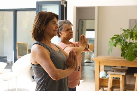 Mature Women Practicing Yoga Indoors in Sunlit Living Space