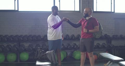 African american men fist bumping in gym after workout showing camaraderie and strength