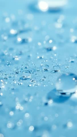 Vertical macro video racking focus revealing water droplet on blue fabric with bokeh