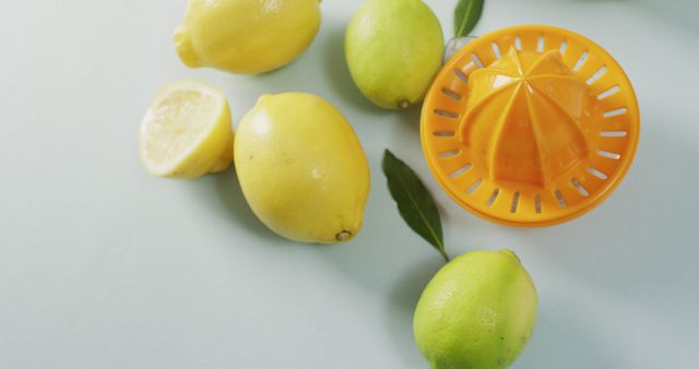Manual citrus juicer and fresh lemons on modern surface. Ideal for use in healthy living blogs, recipe books, advertisements, and culinary websites. Represents freshness, home cooking, and the preparation of homemade juices.