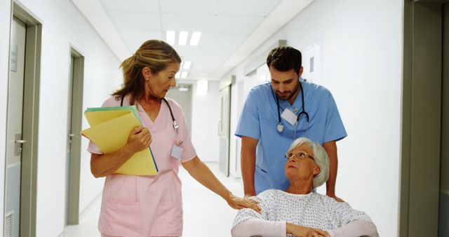 Healthcare professionals providing care to an elderly female patient in a wheelchair in a hospital hallway. Ideal for use in medical care, patient support, healthcare services, and nursing contexts. Can illustrate the dedication of healthcare workers and the importance of patient assistance.