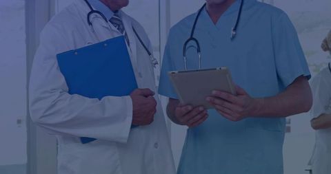 Doctor and Nurse Consulting with Tablet and Clipboard in Hospital Corridor