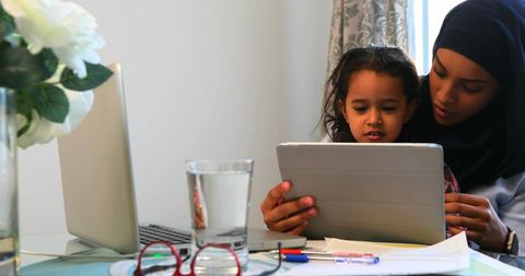 Mother and Daughter Using Digital Tablet at Home Office